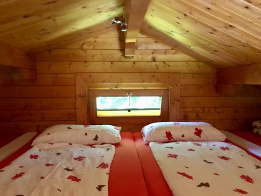 Schlafboden Gemütliches Schlafzimmer mit zwei Betten und einem Fenster in einer Holzhütte.