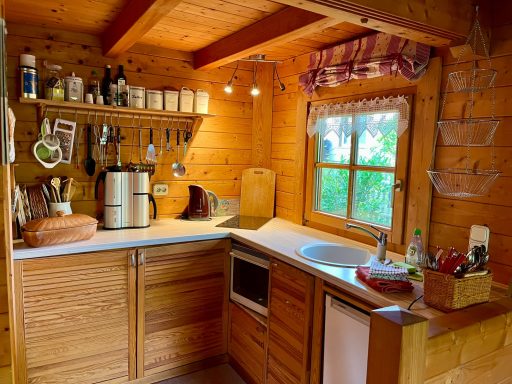 Küche Kleine, gemütliche Holz-Haushaltsküche mit einer Fensteransicht und Küchenutensilien.