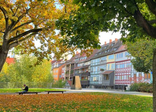 Krämerbrücke Erfurt Bunte Herbstblätter um einen ruhigen Park mit historischen Gebäuden im Hintergrund.