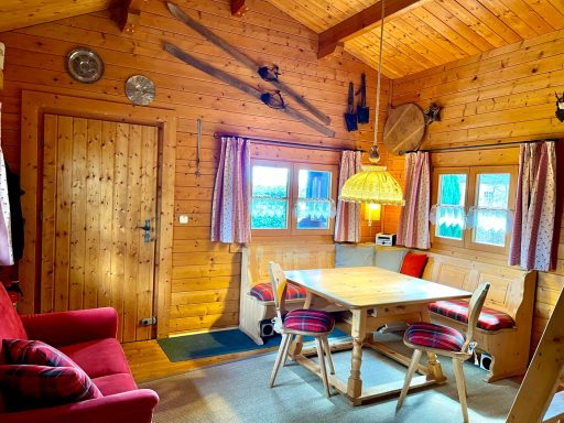 Wohnraum Gemütlicher Raum mit Holzwänden, Tisch, Stühlen, Sofa und traditionellen Skiern an der Wand.