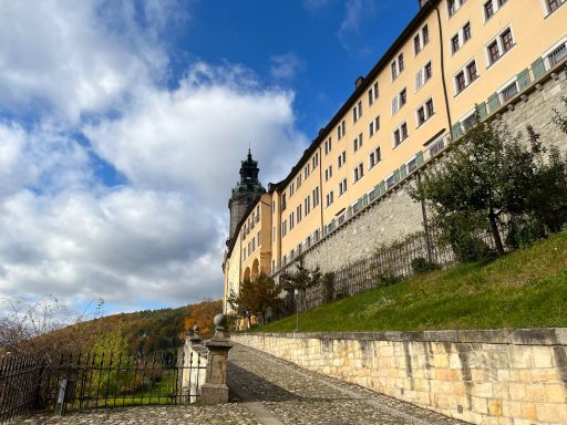 Residenzschloss Heidecksburg Rudolstadt Historisches Schloss mit Steinfassade, umgeben von Garten und blauem Himmel.
